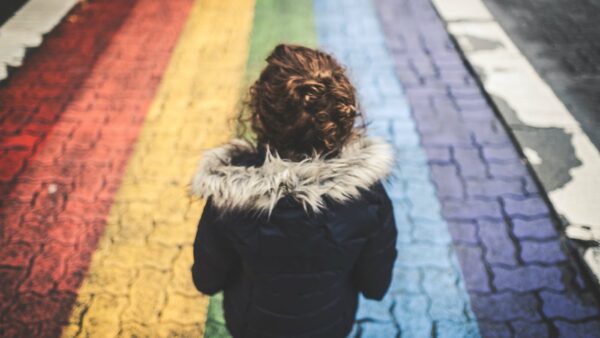 Bambina cammina su asfalto colorato di arcobaleno
